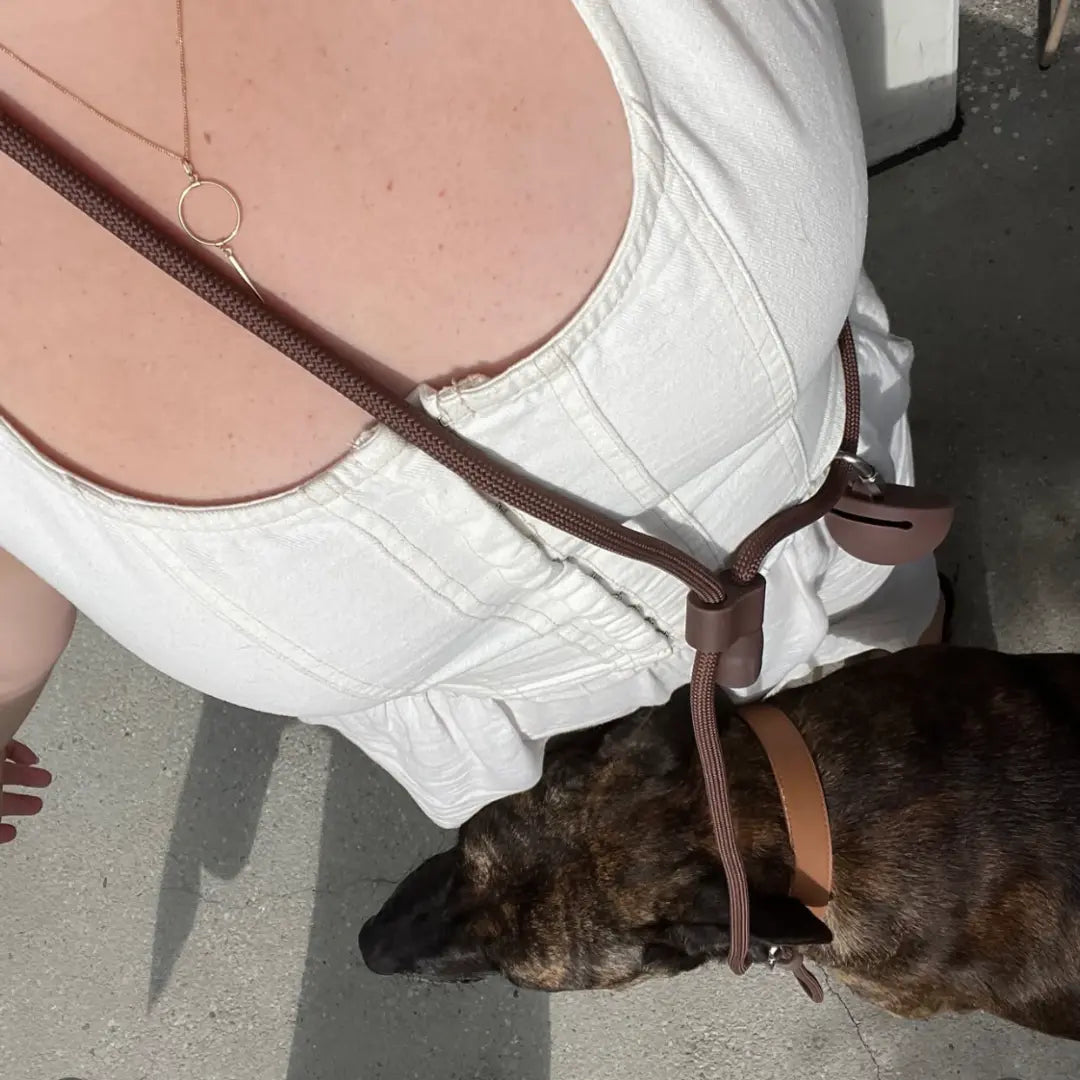 Opiekun w terenie, smycz St. Argo Hands-Free czekoladowa przewieszona przez tułów.
